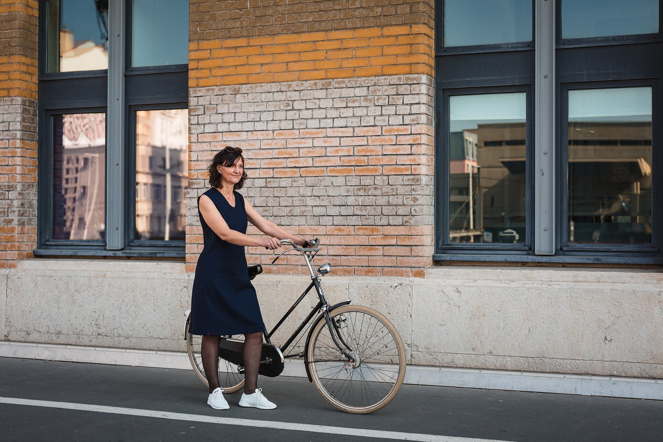 Une femme en vélo dans Lyon habillée en robe personnalisable Laurence Glorieux.