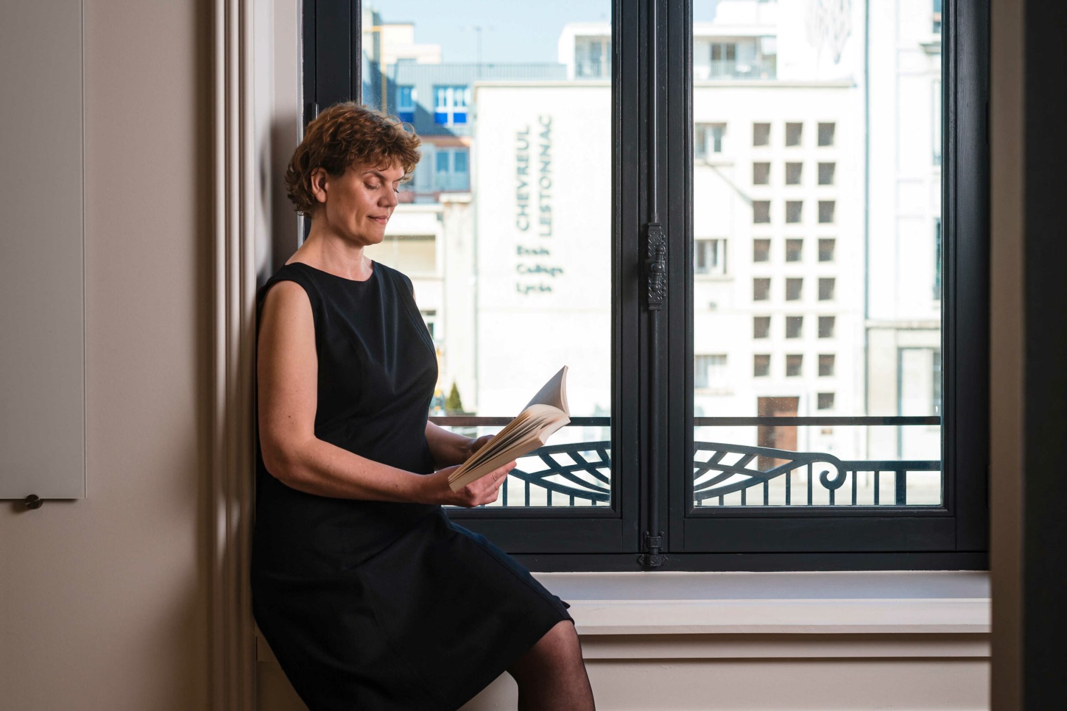 Une femme vêtue d'une robe noire Laurence Glorieux lisant un livre .